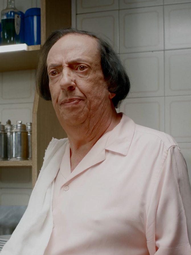 Personagem atrás do balcão de um bar, cena de comercial de humor