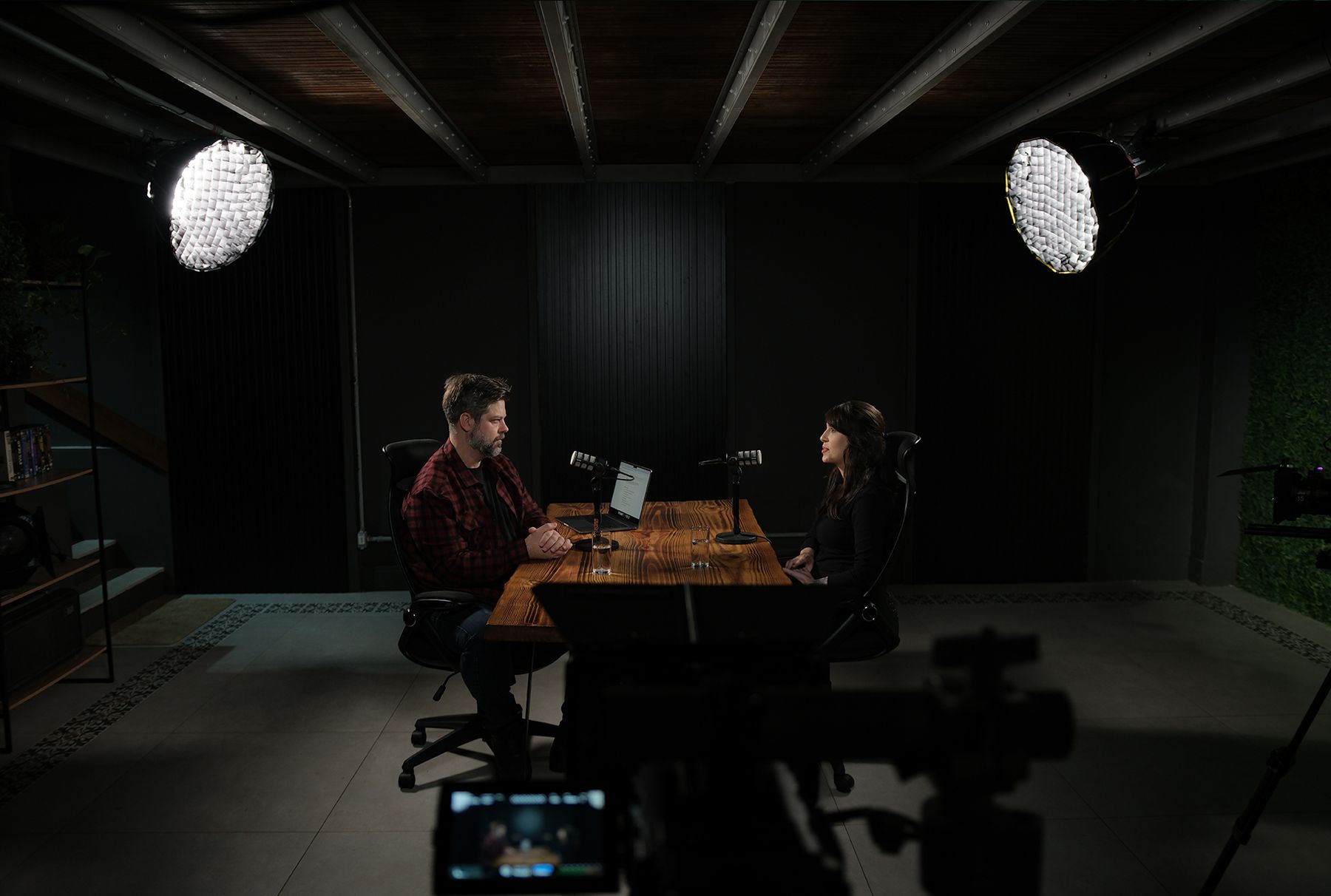 Entrevista gravada no estúdio com dois refletores e mesa de madeira