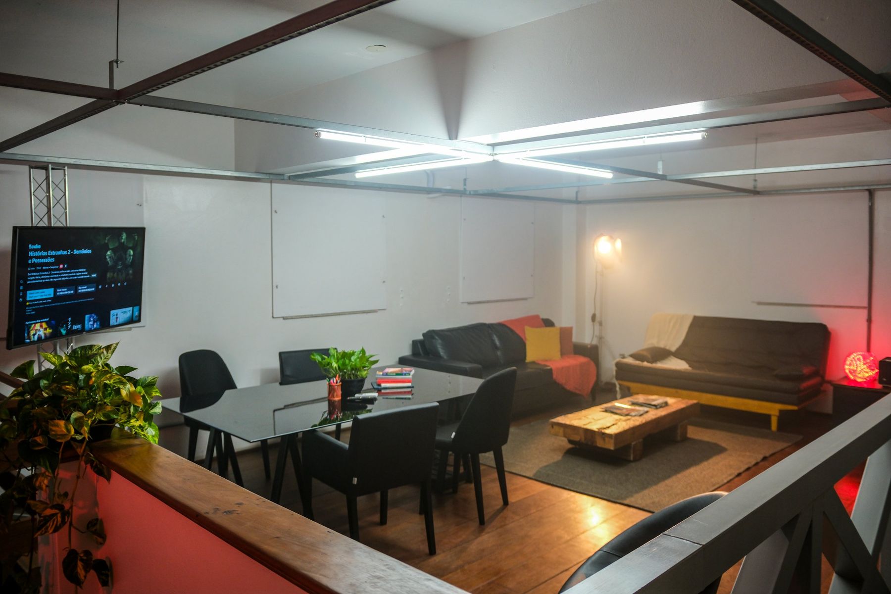 Sala de reunião do estúdio com mesa, sofás e televisão