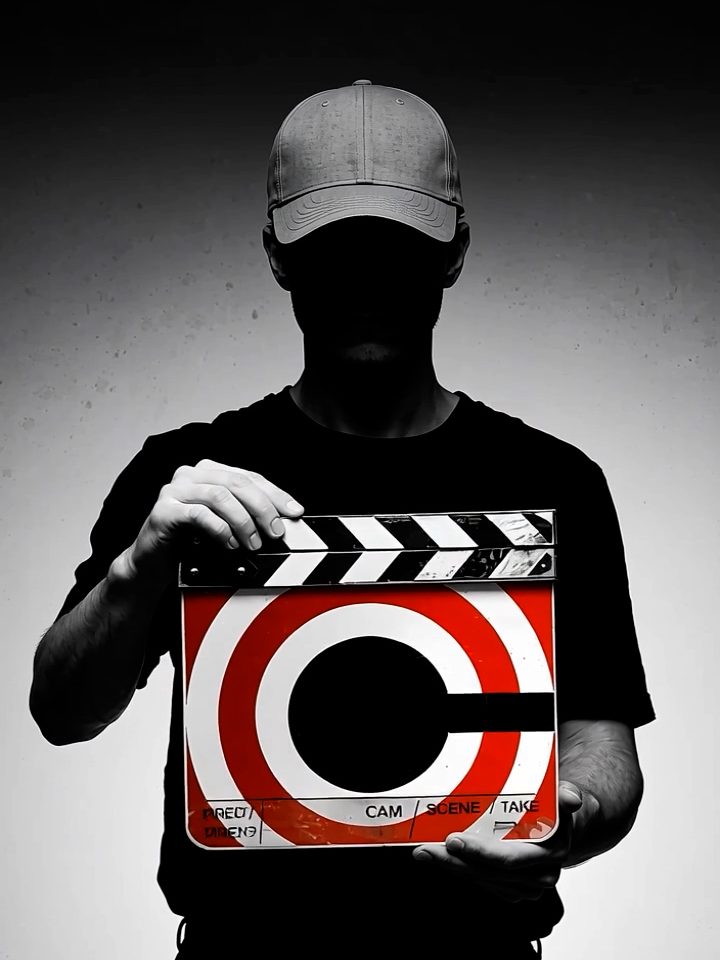 Diretor segurando claquete com a marca da Cinematográfica, em preto e branco