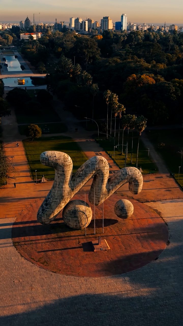 Vista aérea de escultura monumental em parque de Porto Alegre ao entardecer, vídeo vertical com IA