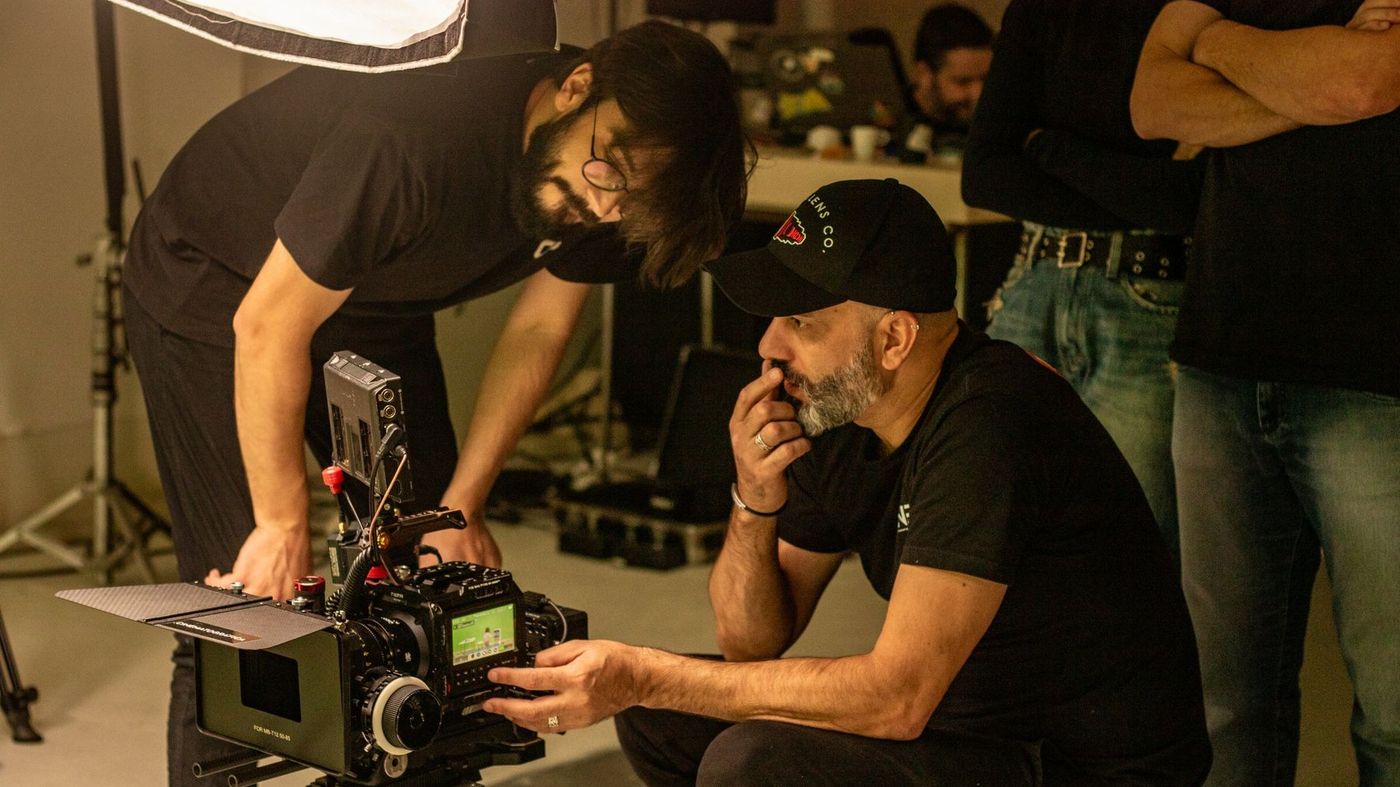 Diretor e diretor de fotografia conferindo o enquadramento no monitor da câmera de cinema durante gravação