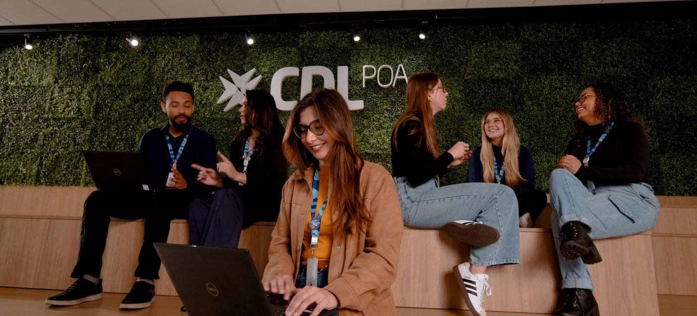 Equipe da CDL POA reunida em frente à parede verde com o logotipo, cena de vídeo institucional